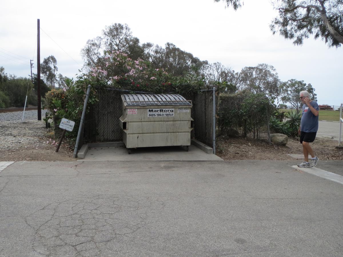 Dumpster inside a designated area marked by 3 fences