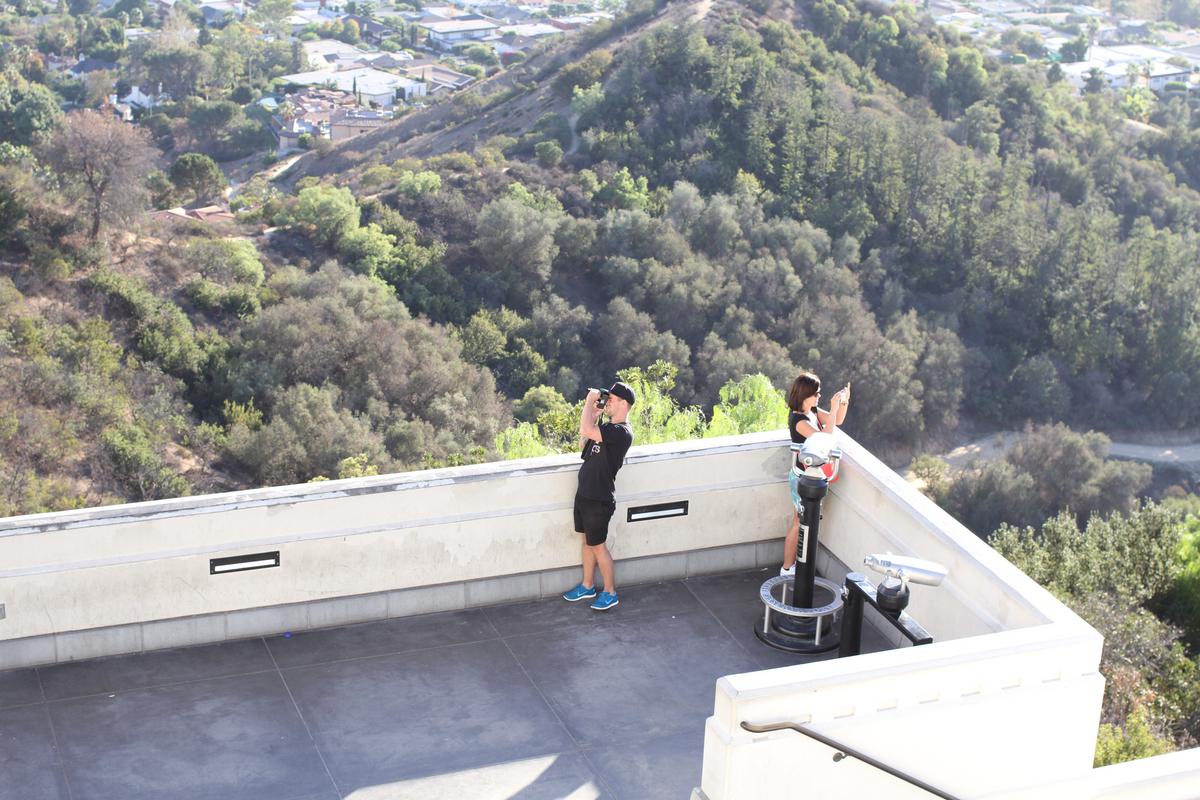 Two people facing away from eachother taking photos at an overlook